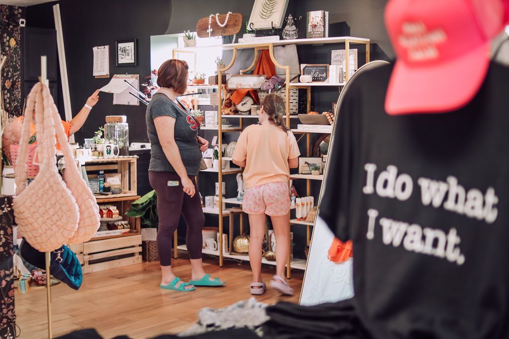 Inside a gift shop, shoppers browse merchandise.  A black t-shirt with 
