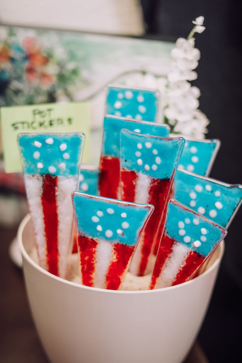 Glass flag-themed pot stickers in a white container, with red and white stripes and blue starry tops.