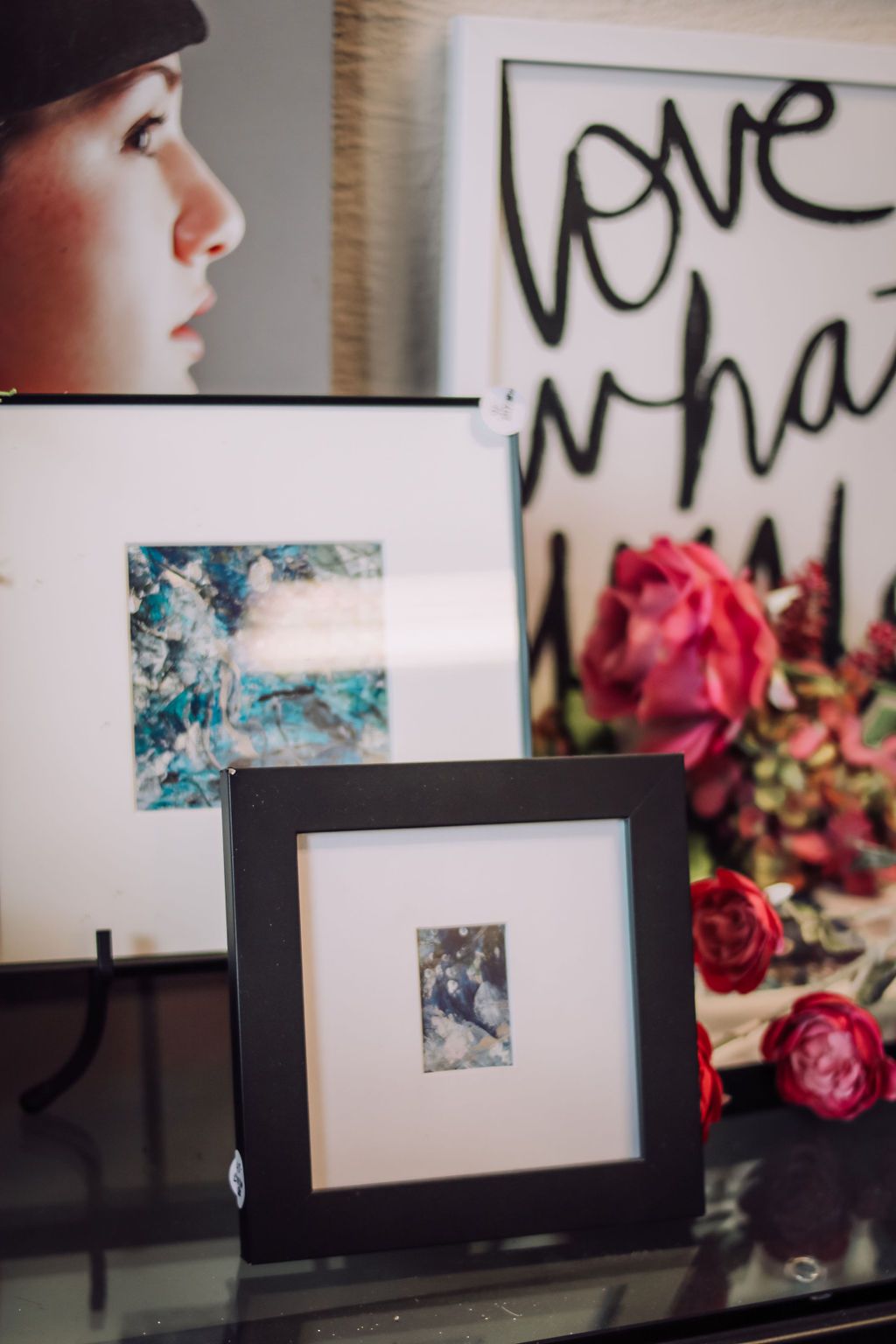 Artwork display with framed pictures, floral arrangement, and a profile portrait.