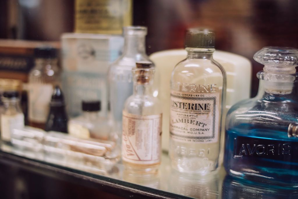 Bottles of different sizes on a glass shelf. One reads 