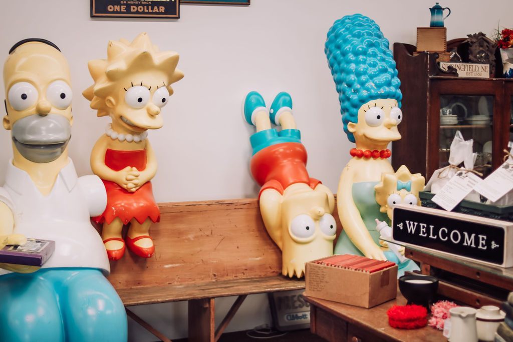 Simpson family statues: Homer, Lisa, Bart upside down, Marge. Displayed with a 