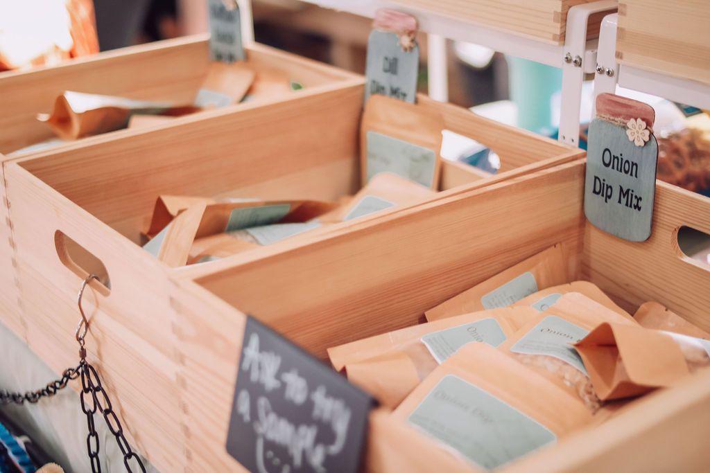 Wooden crates filled with sealed bags of dry goods, possibly dips, at a market stall.
