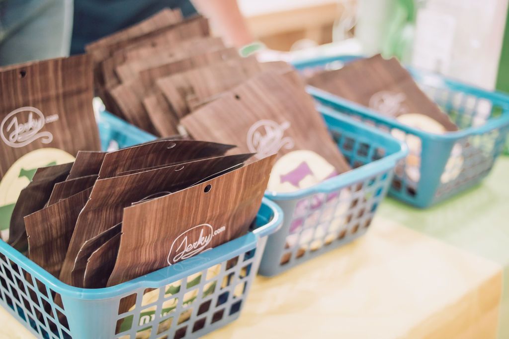 Brown packaged products in blue plastic baskets on a table.