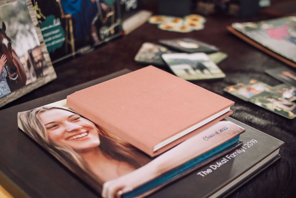 Several photo albums displayed on a table; one pink, others with photos of people and horses.