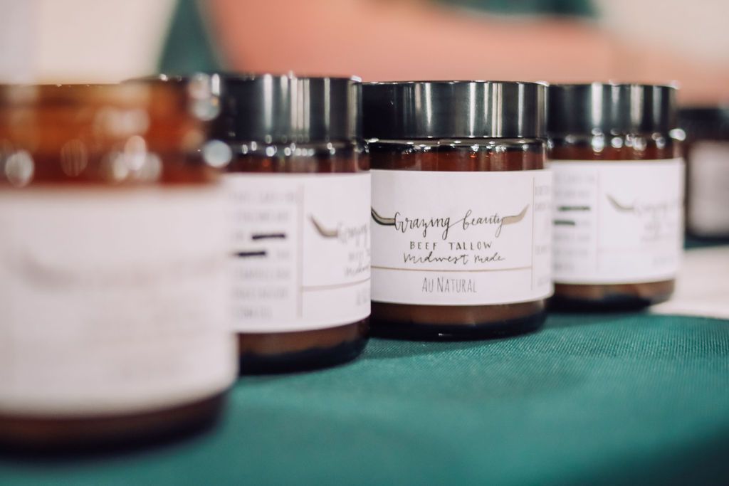 Brown jars with black lids and white labels, arranged on a green surface.