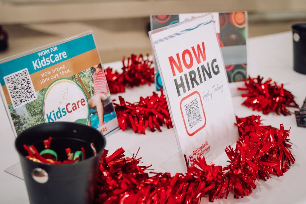 Table with hiring signs and red garland, including 
