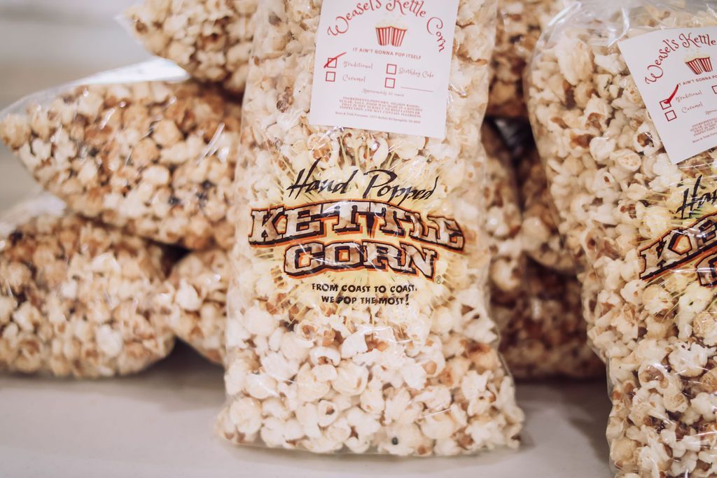 Bags of kettle corn, a light-brown and white snack, with a label featuring branding.