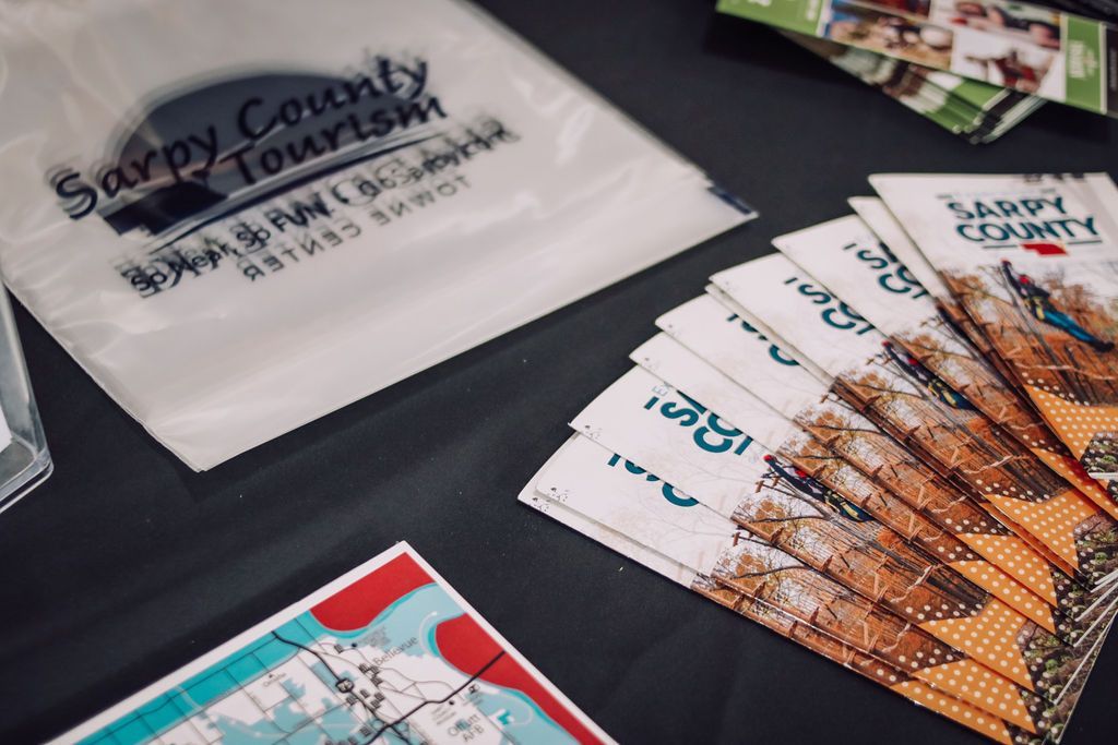 Sarpy County Tourism brochures, map, and bag on a dark surface.