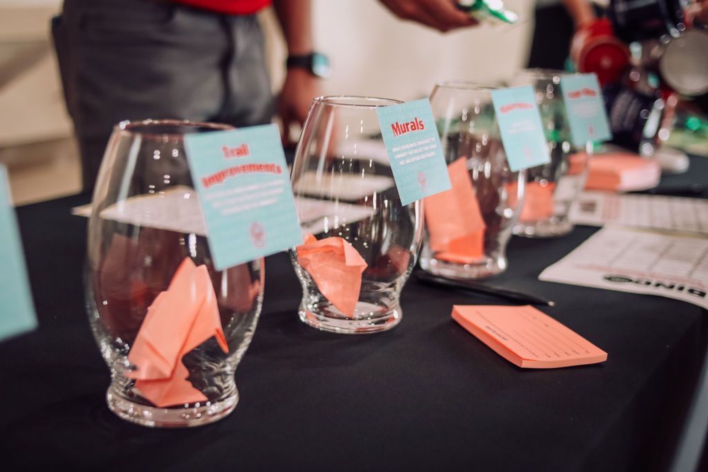 Glass bowls with pink papers on a table, a person's hands holding an item in the background.
