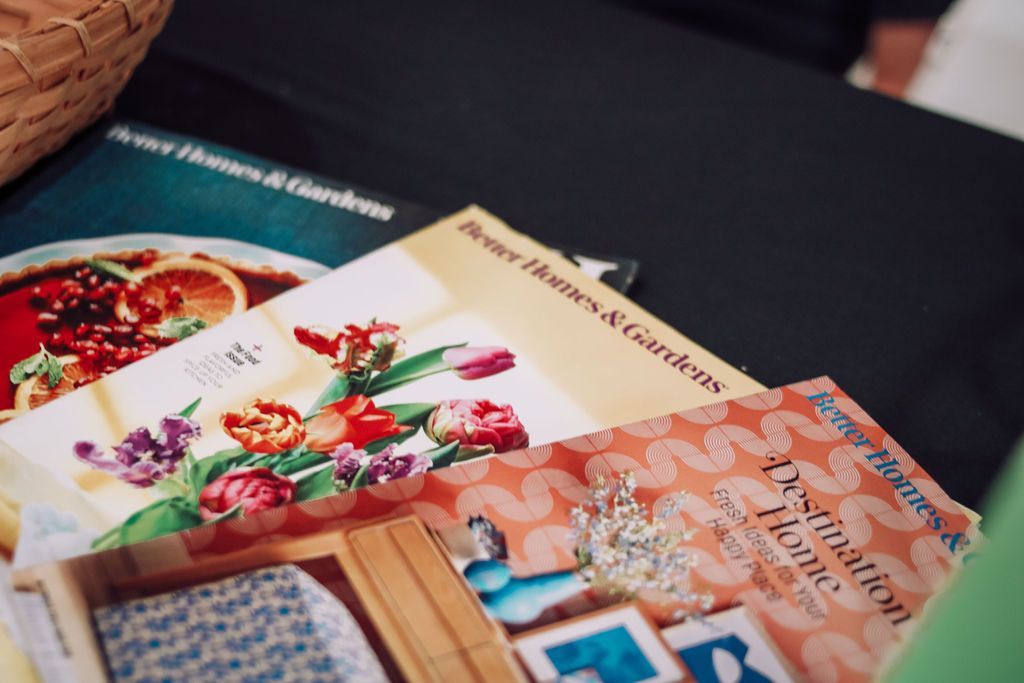 Magazines, with floral, food, and home design covers, on a dark surface.