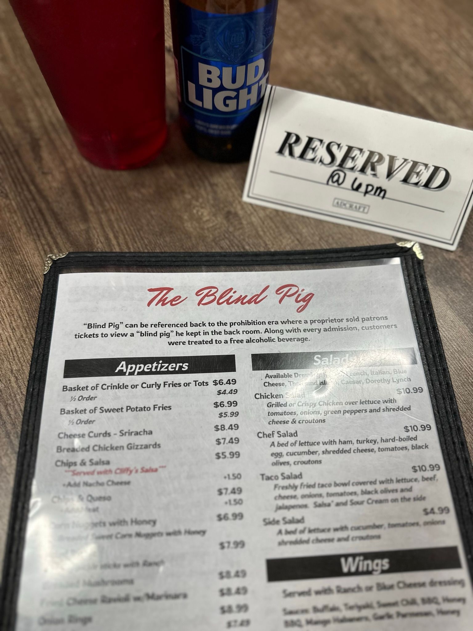 Menu, Bud Light bottle, drink, and reserved sign on a table in The Blind Pig.
