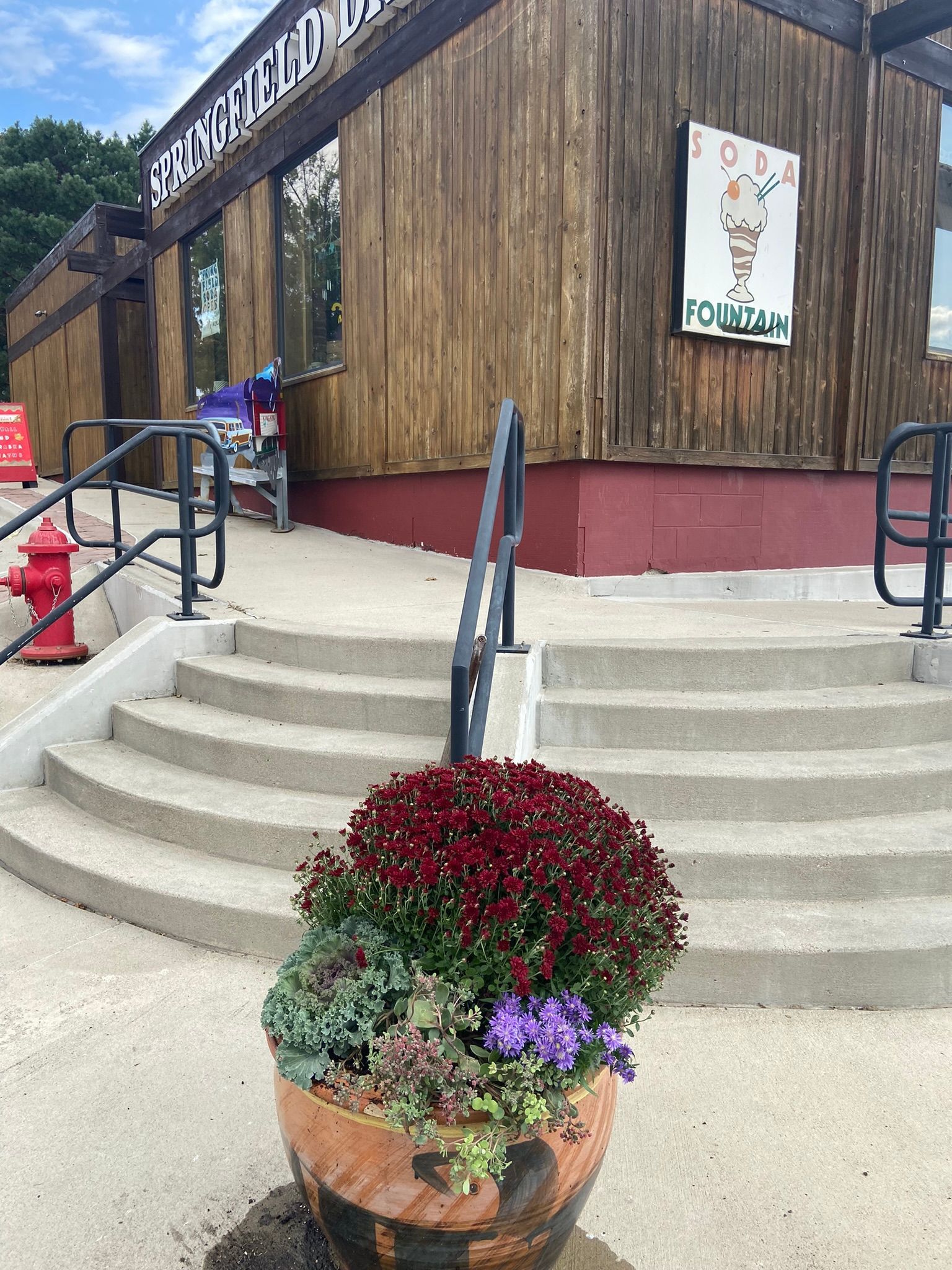 Exterior of ice cream shop with flower pot in front of steps. Building has a bamboo-like exterior.