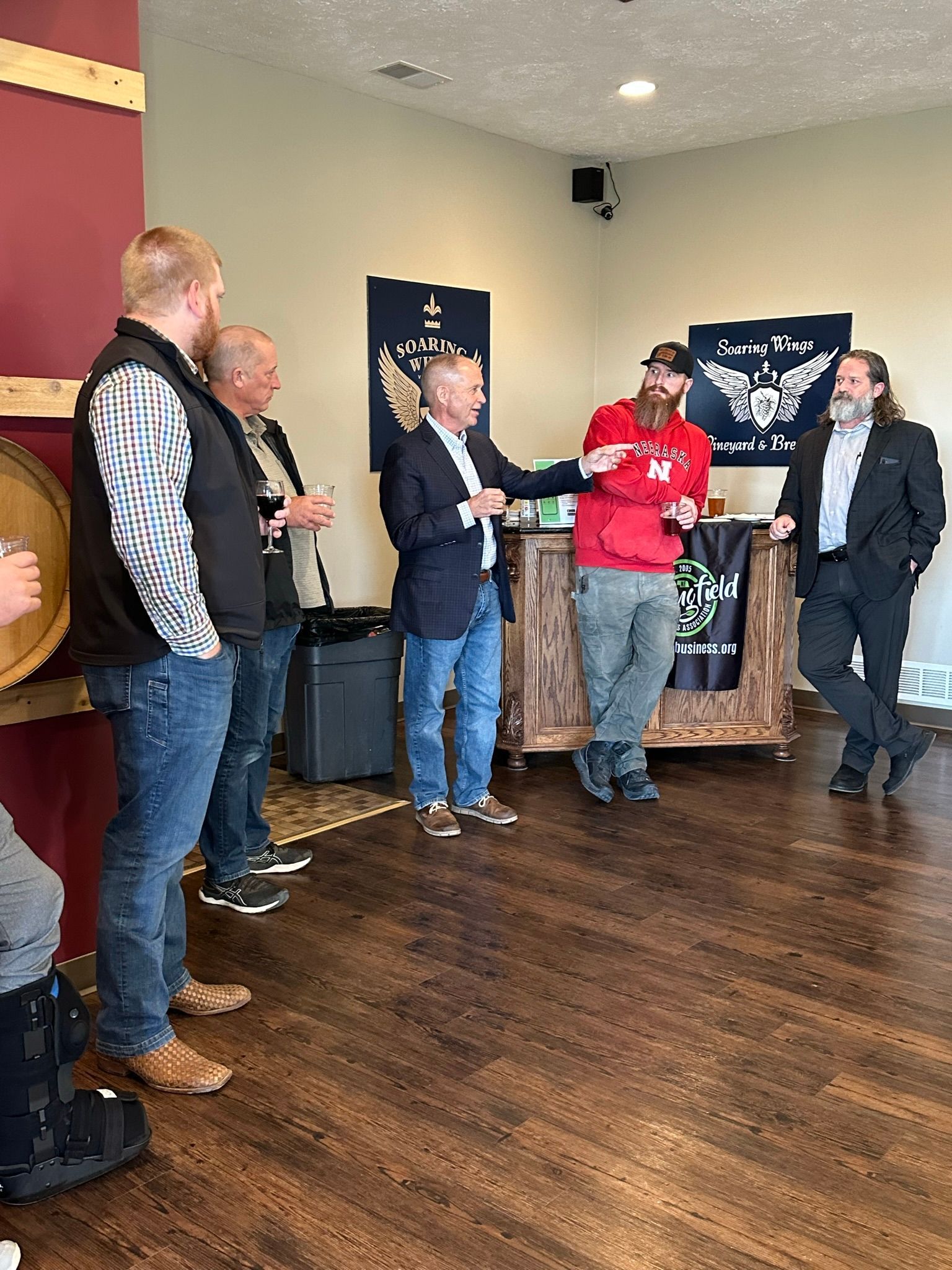 Men in a room, presenting an award. The person in a red shirt is receiving the award.