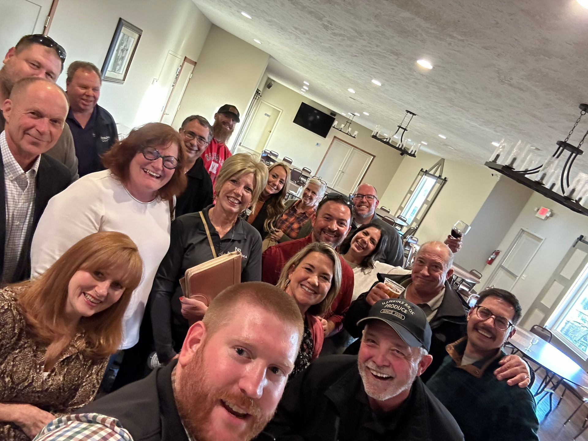 Group of people smiling, posing for a photo indoors. Bright lighting. Happy expressions.