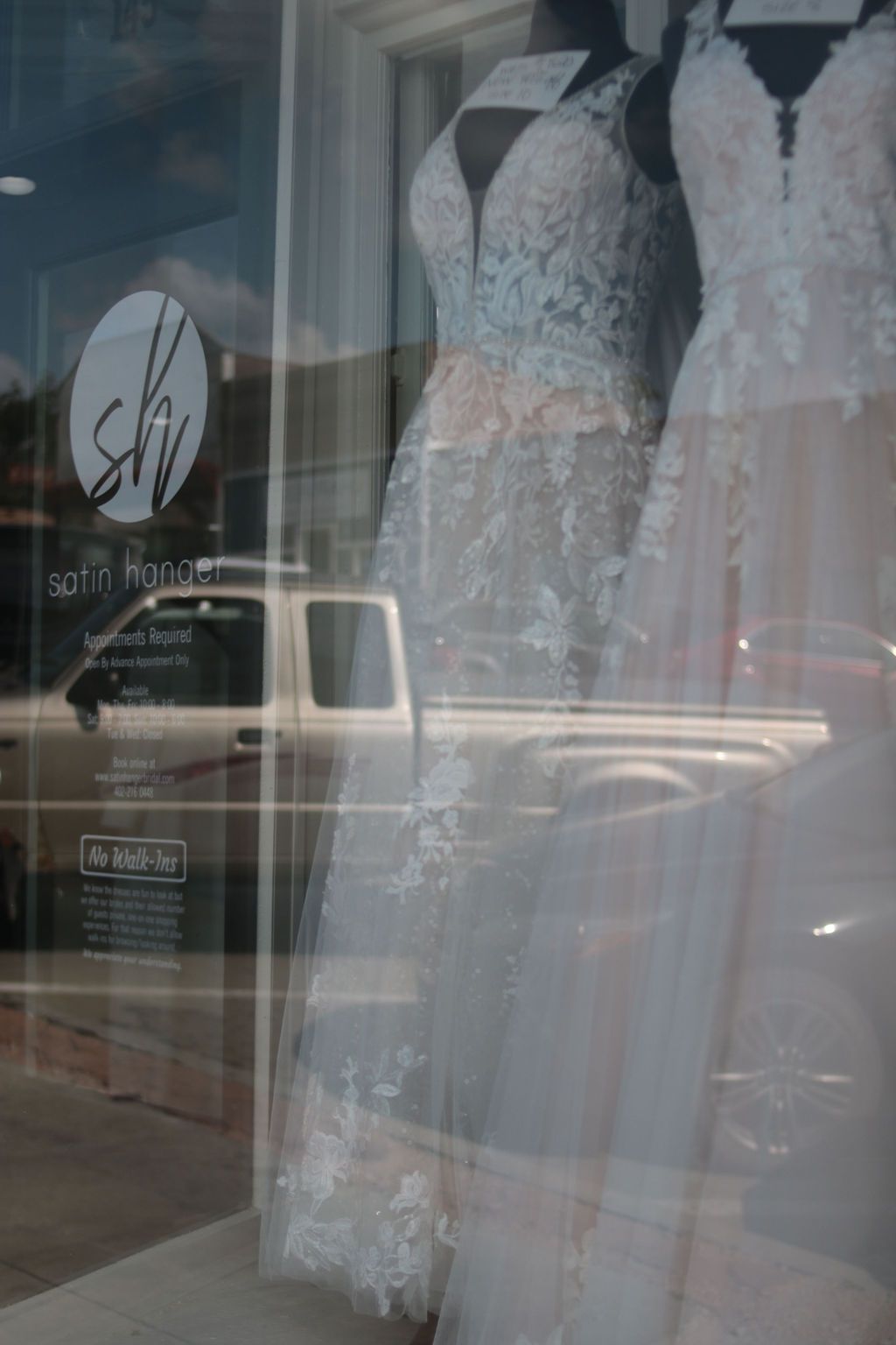 Wedding dresses in shop window, reflected street view.