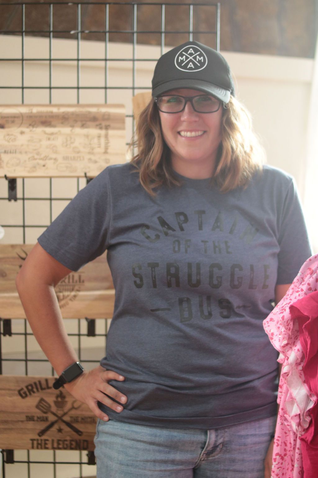 Woman smiling, wearing a hat and shirt that says 