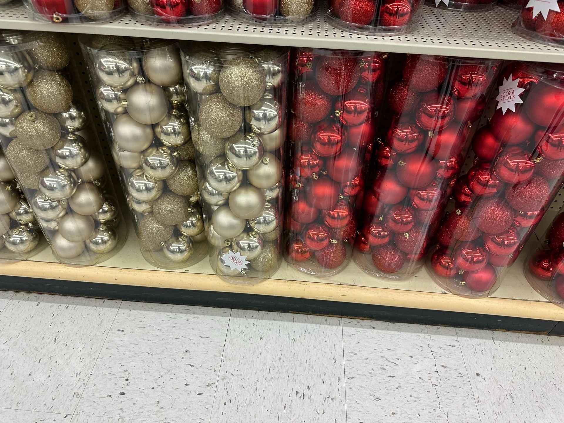 Shelves with clear plastic tubes filled with gold, silver, and red Christmas ornaments.