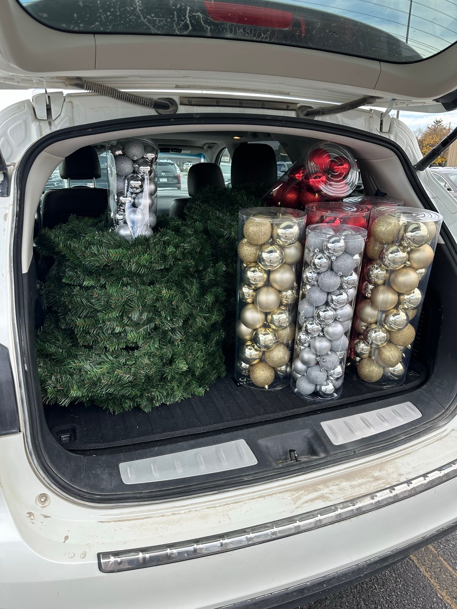 Car trunk loaded with Christmas decorations, including ornaments and a tree.