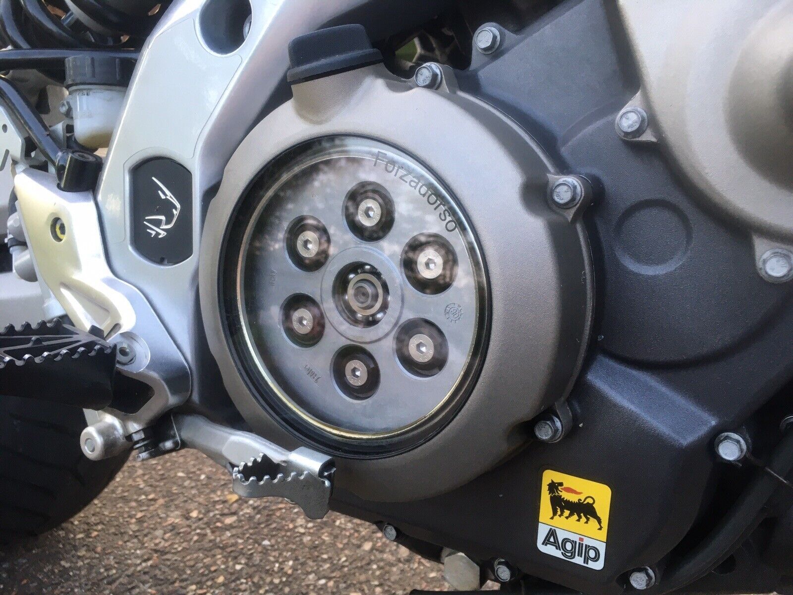 A close up of the transparant clutch cover installed on an Aprilia Dorsoduro 750.