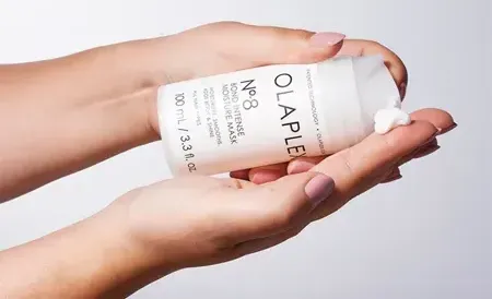 A woman is holding a bottle of lotion in her hands.