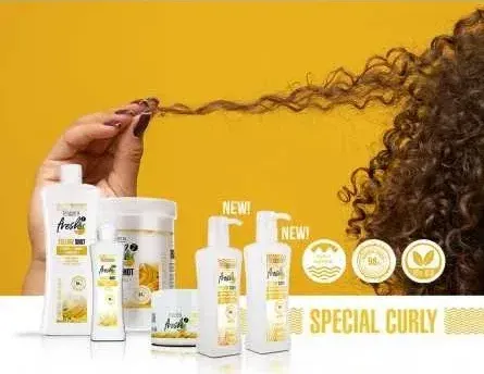 A woman with curly hair is holding a bottle of shampoo.