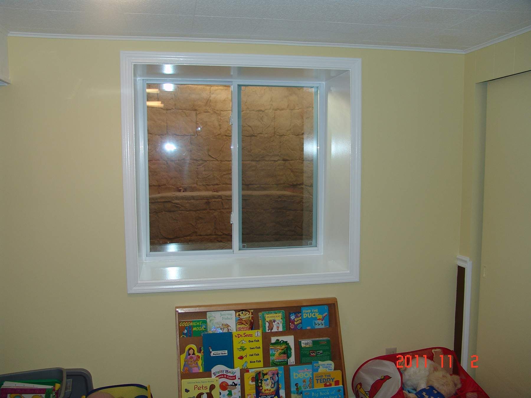 A house under construction with a window well in the ground.