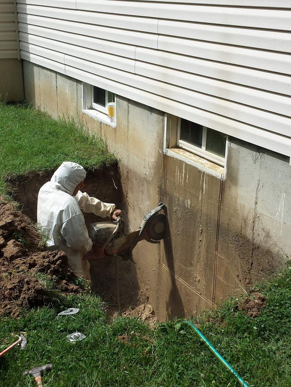 A man is digging a hole in the side of a house.