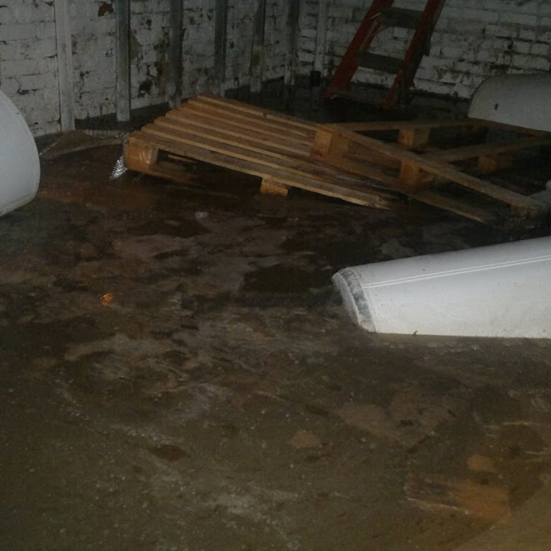 Large sewer backup flood in a basement with pallets and plastic bins floating