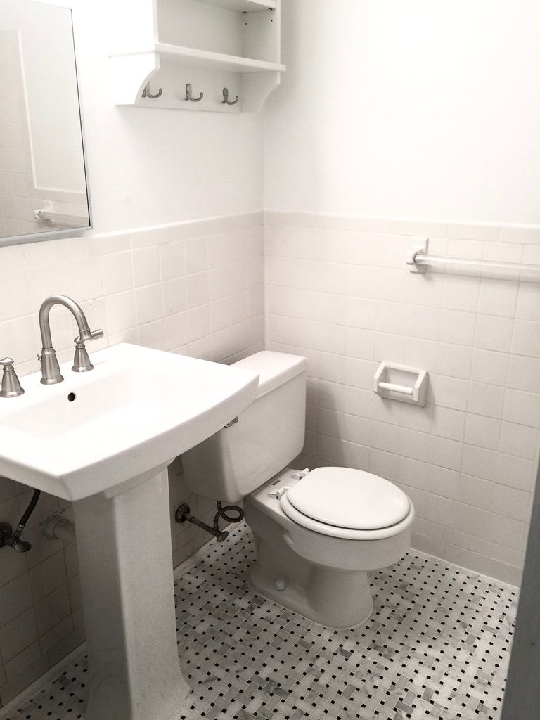 A bathroom with a toilet , sink and mirror.