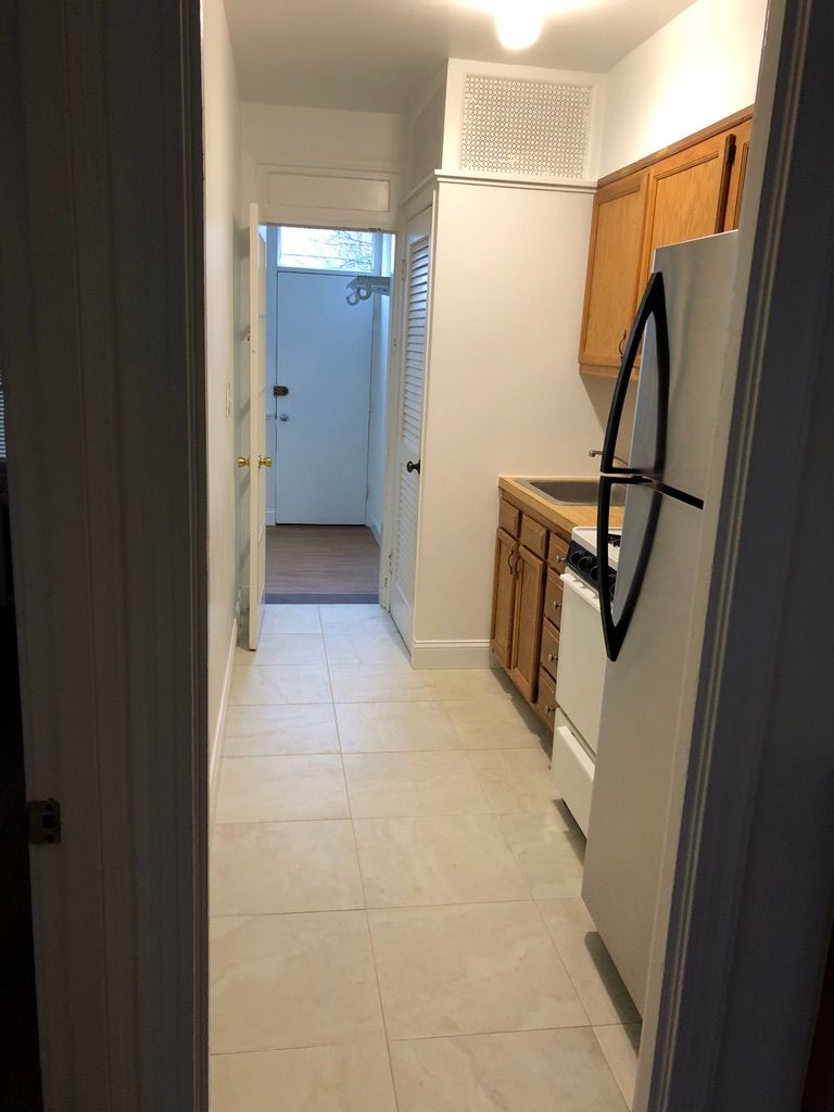 A kitchen with a refrigerator , stove , sink and cabinets.