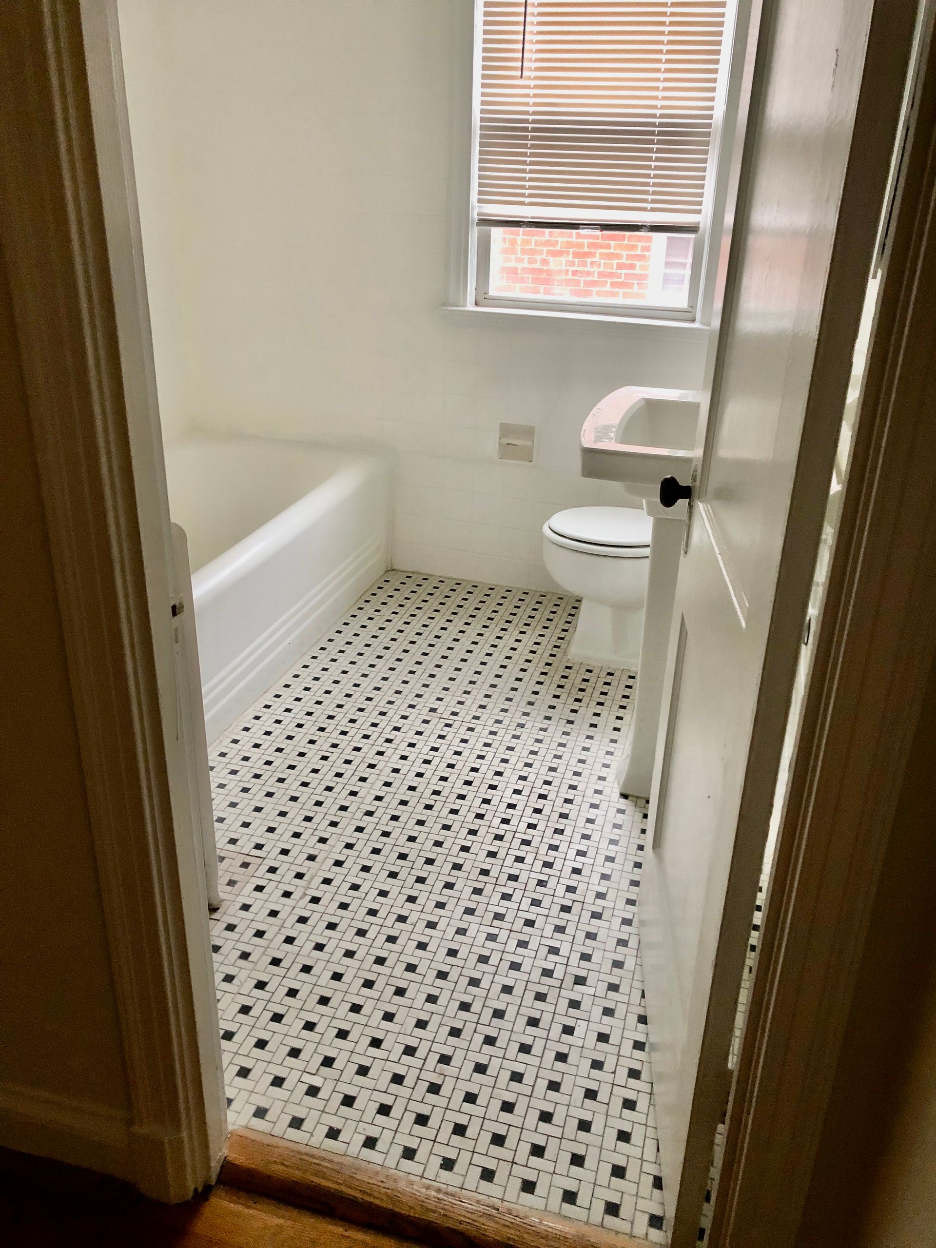 A bathroom with a toilet , bathtub , sink and window.