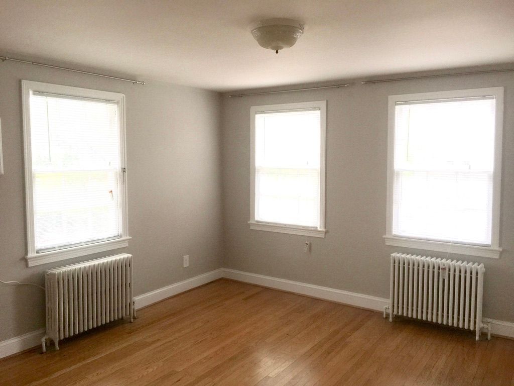 An empty room with two radiators and three windows.
