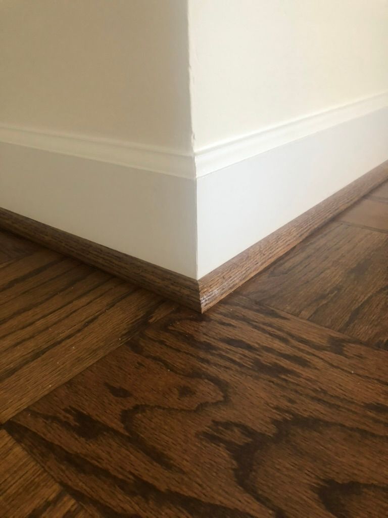 A corner of a room with a wooden floor and white trim.