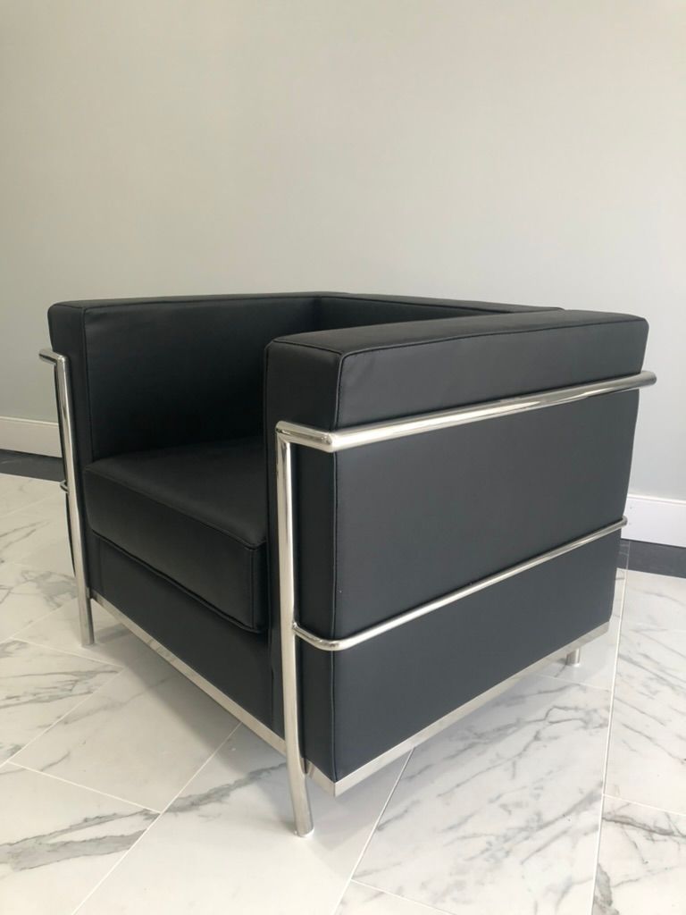 A black leather chair is sitting on a marble floor.