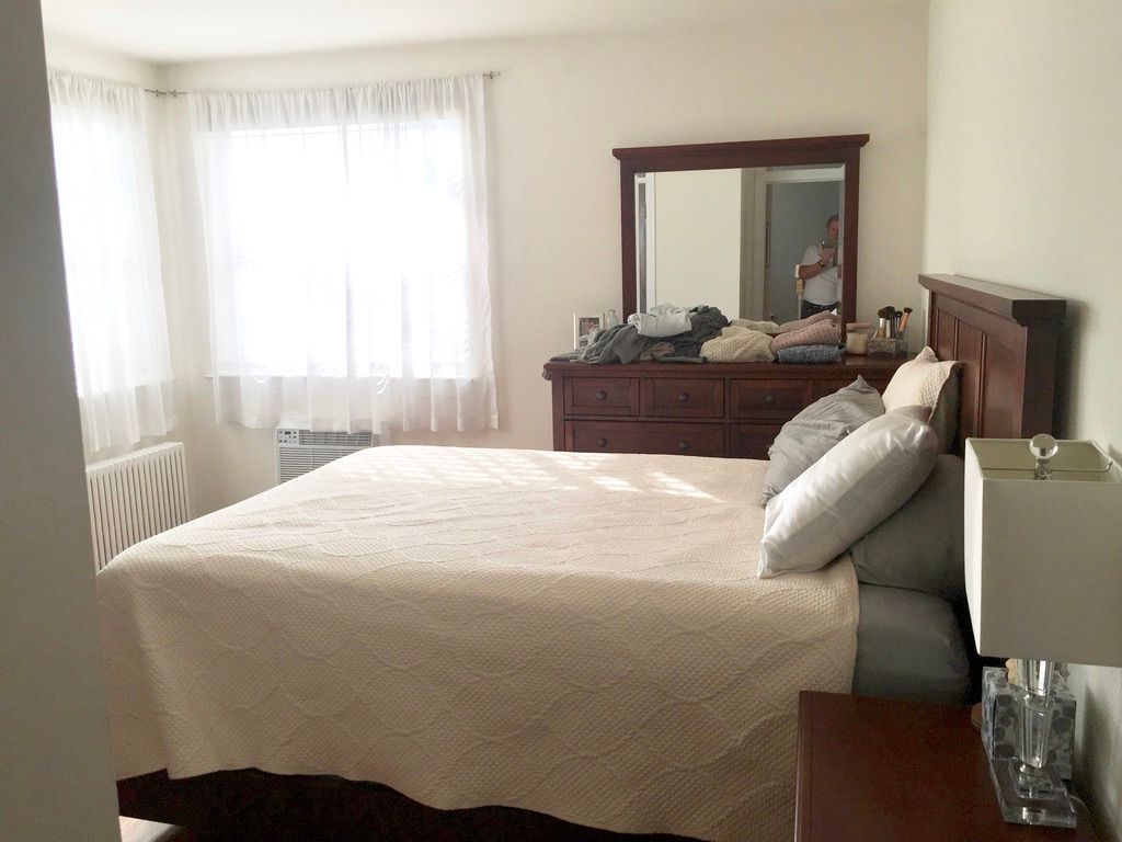 A bedroom with a bed , dresser and mirror