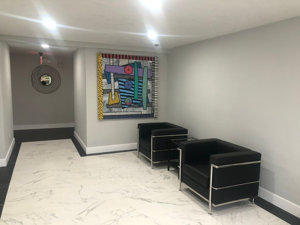 A hallway with two chairs and a large painting on the wall.