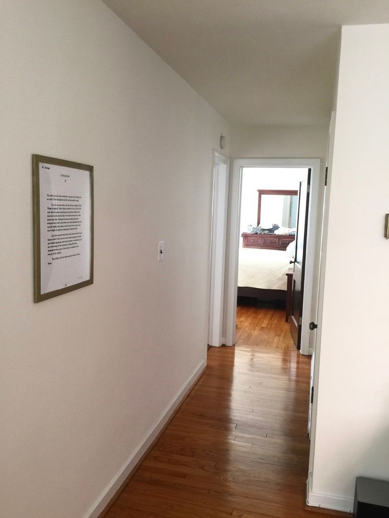 A hallway leading to a bedroom with a picture on the wall