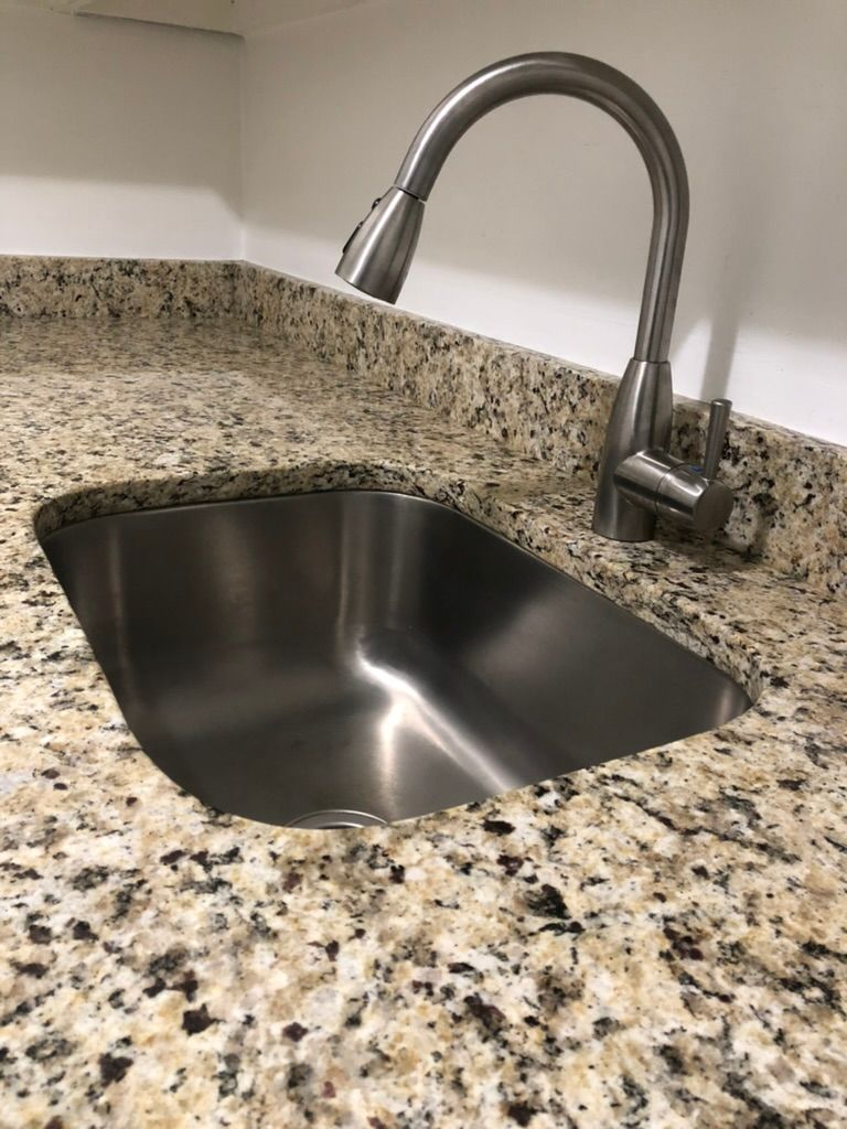 A stainless steel sink is sitting on top of a granite counter.