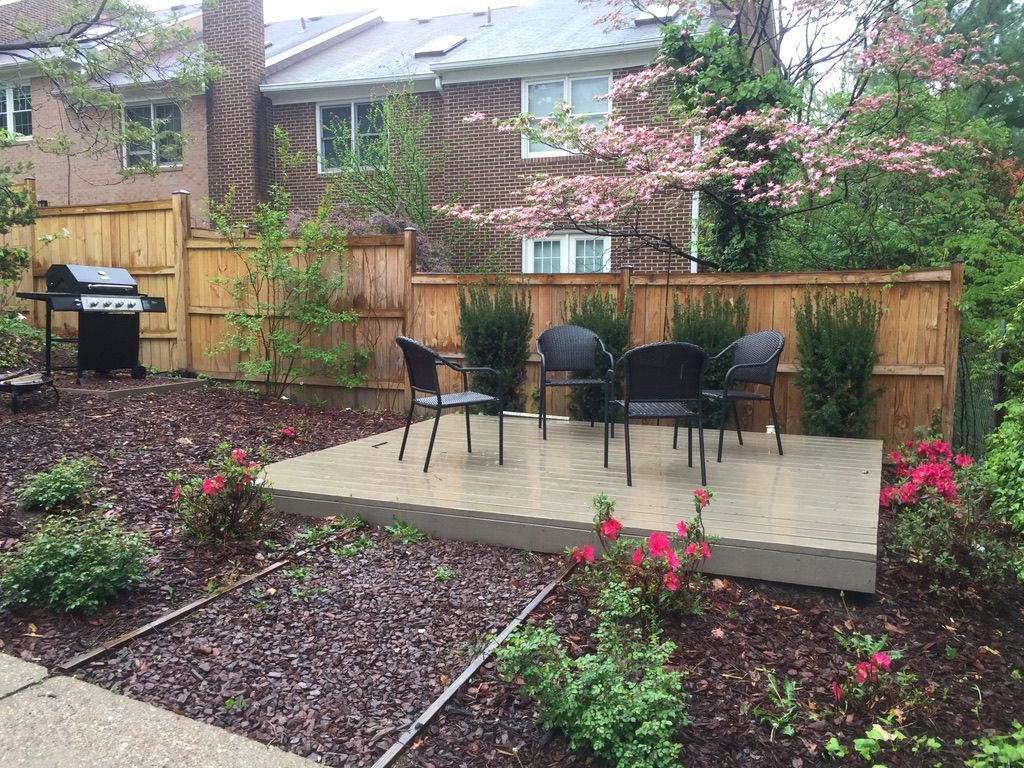 A backyard with a table and chairs and a grill.