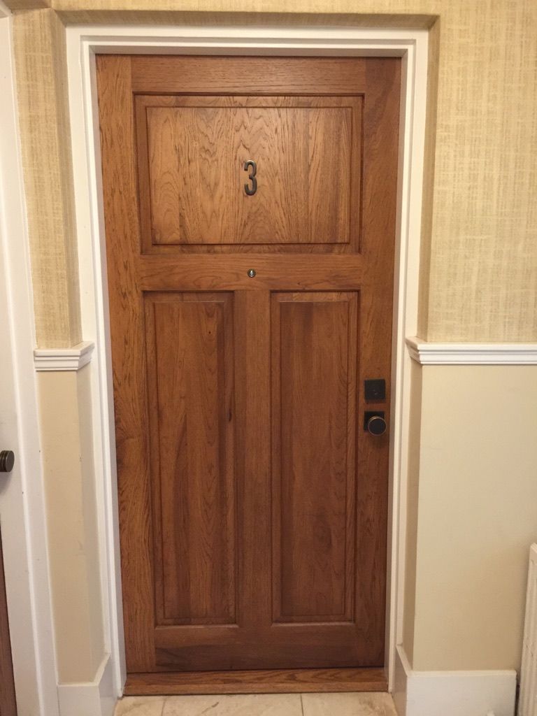 A wooden door with the number 3 on it is in a hallway.