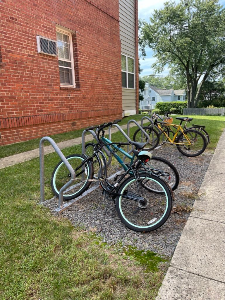 A row of bicycles are parked on a bike rack in front of a brick building.