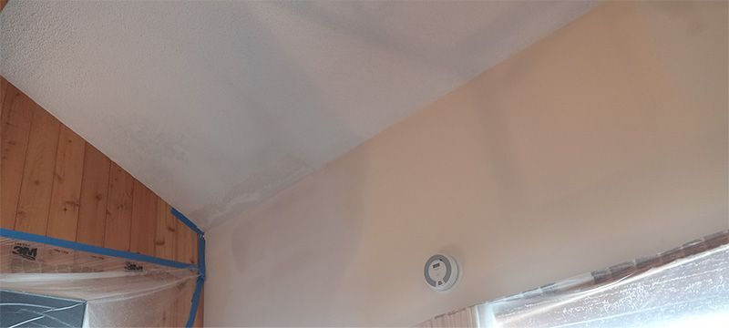 A room with a clock on the wall and a ceiling.