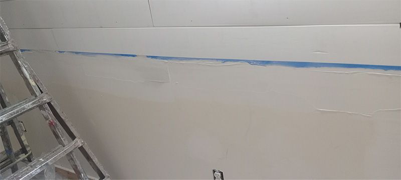 A ladder is sitting on top of a white wall.