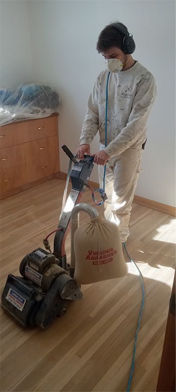 A man is sanding a wooden floor with a machine.