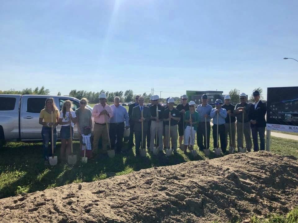 A group of people are standing in a field holding shovels.