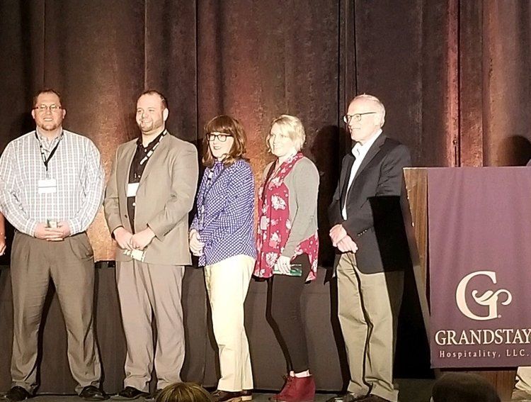 A group of people standing in front of a podium that says grandstay