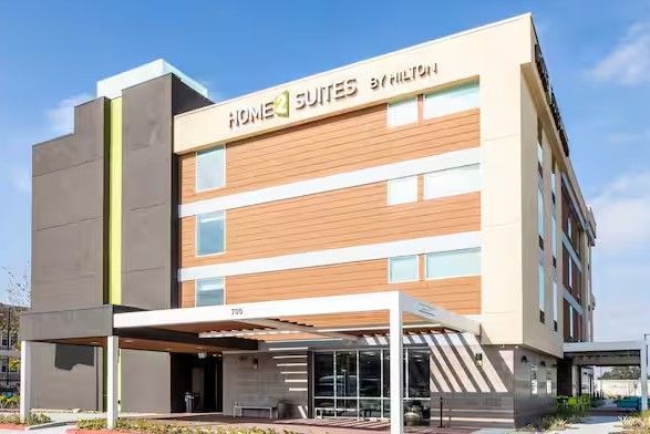 An artist 's impression of a hotel with cars parked in front of it.