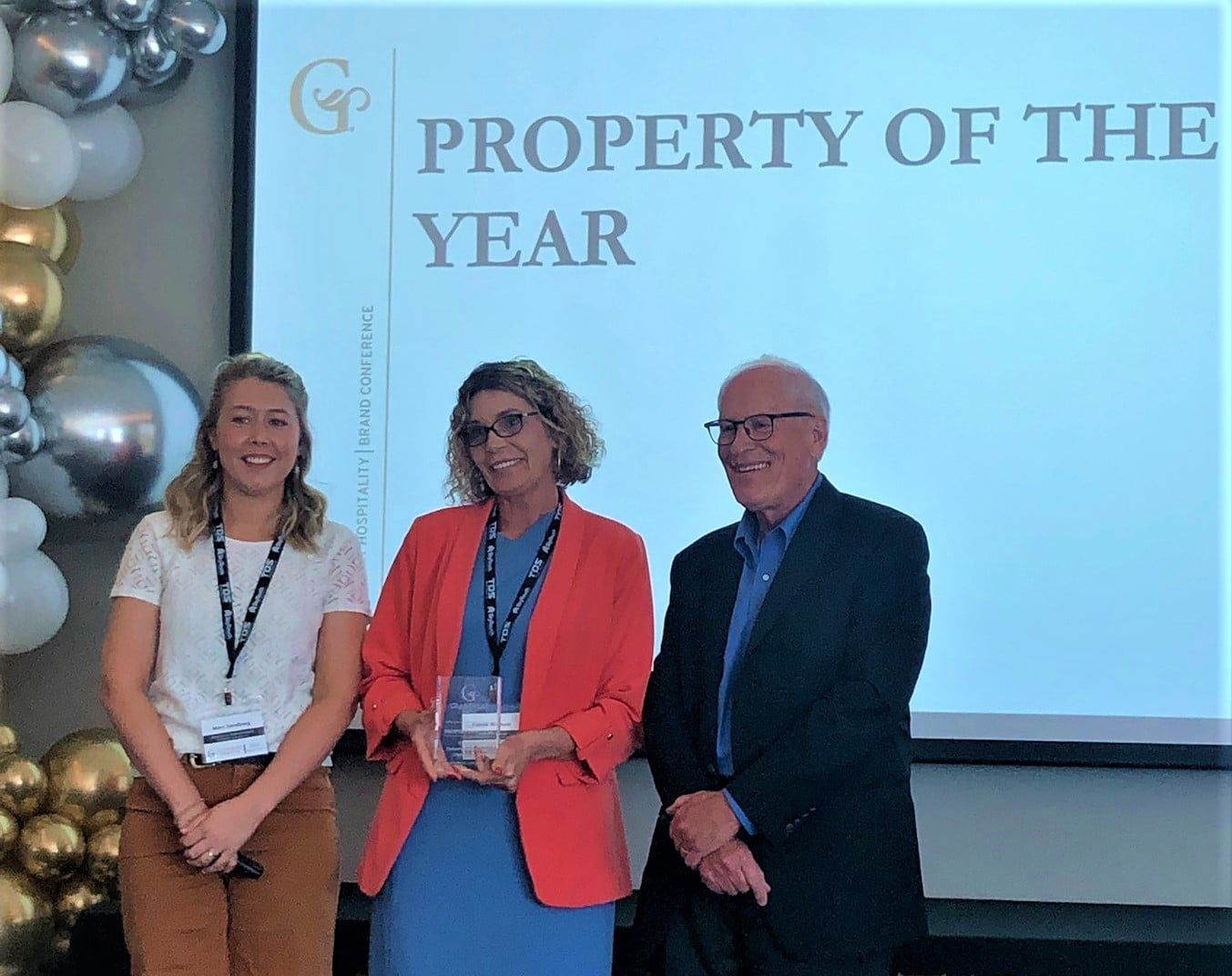Three people are standing in front of a screen that says property of the year.