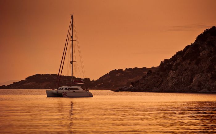 A catamaran surrounded by orange light at sunset