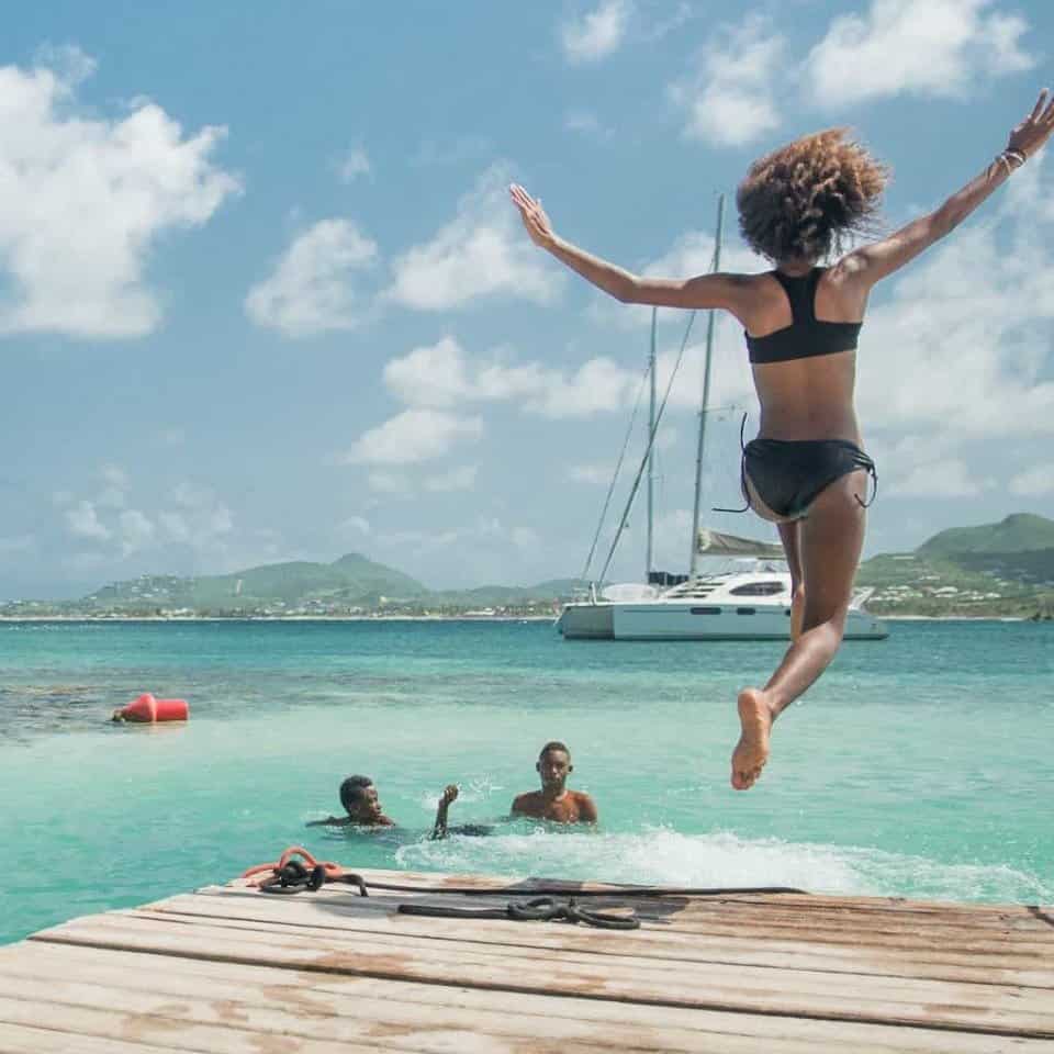 A woman in a bikini is jumping into the ocean.